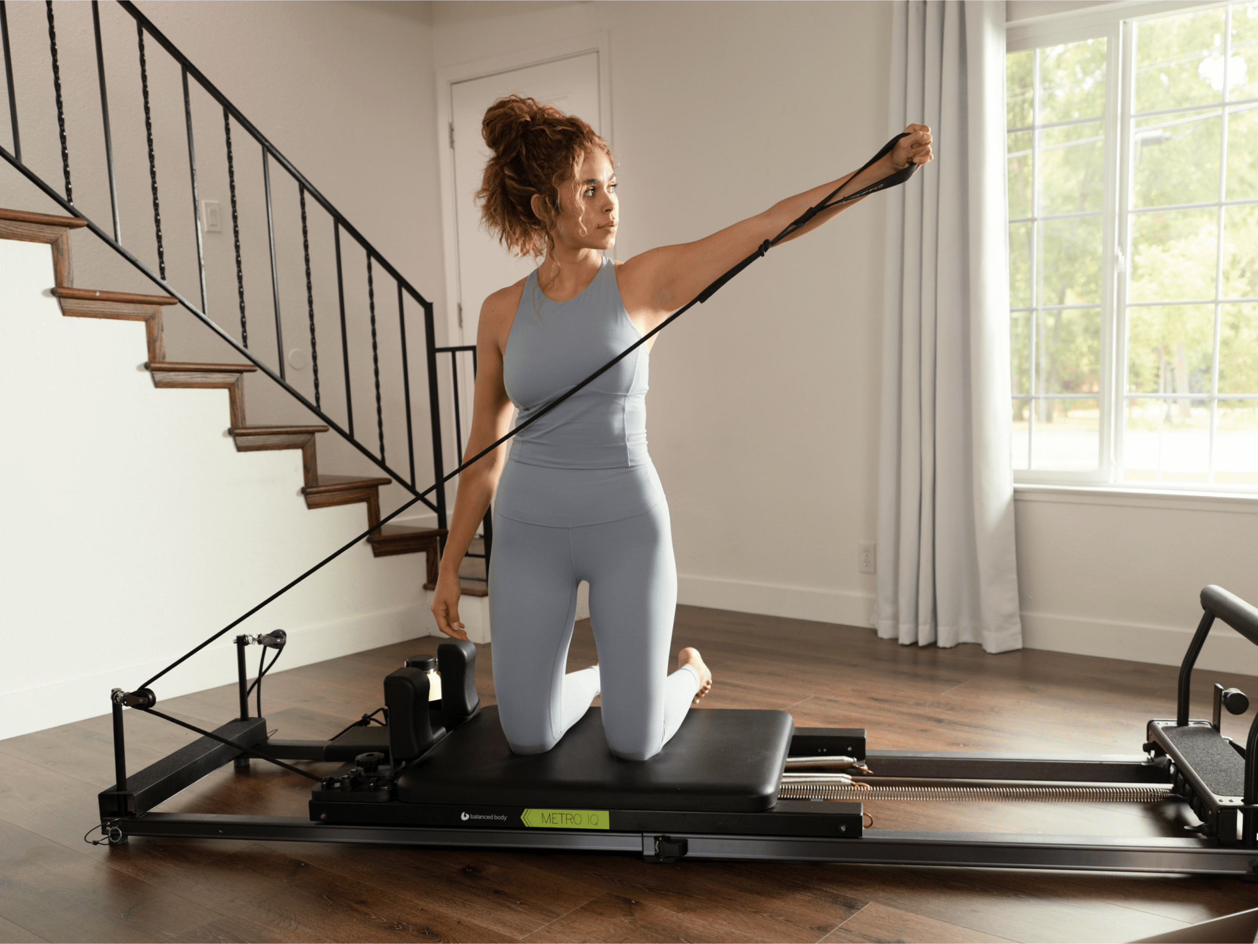 woman using the metro iq pilates reformer in her home